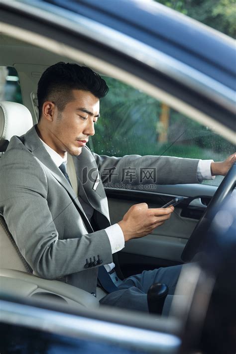 青年男人开车看手机高清摄影大图-千库网