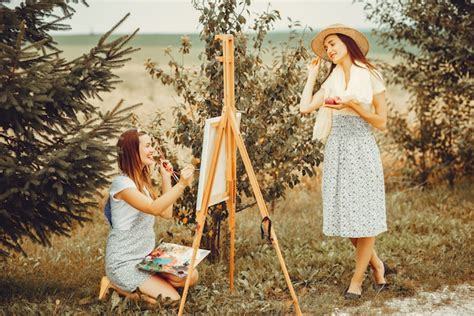Two beautiful girls drawing in a field | Free Photo