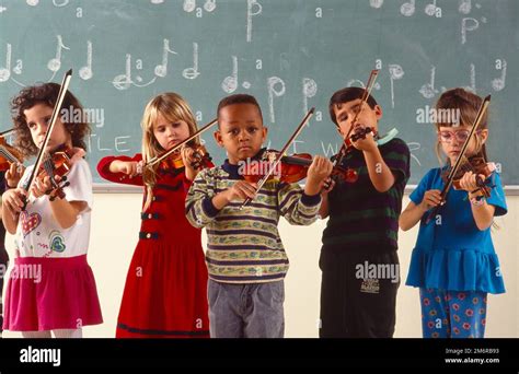 A group of young school-age children, all playing violins in the ...