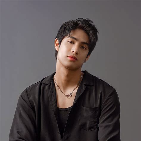 a young man in black shirt sitting down with his hands on his chest and ...