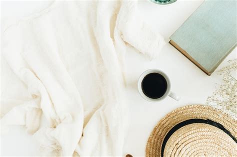 Female office desk with coffee, book, straw hat, flowers and blanket on ...