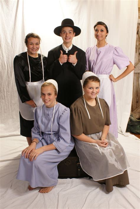 a group of people that are sitting on a bed together in dresses and bonnets