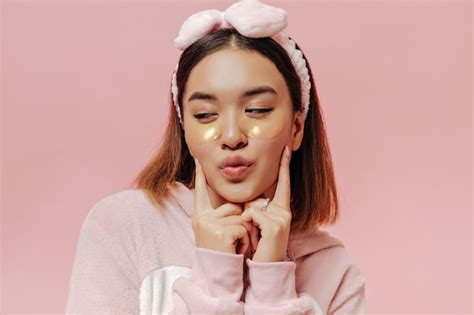 Pretty brunette woman in soft pajamas and headband blows kiss and poses ...