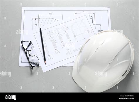 Different engineering drawings, hard hat, pencil and glasses on grey ...
