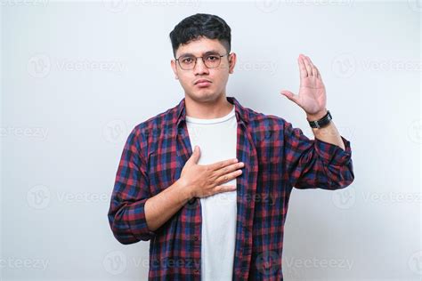 Young handsome asian man smiling swearing with hand on chest and ...