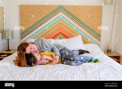 Mother and daughter cuddling on a bed in a kids room