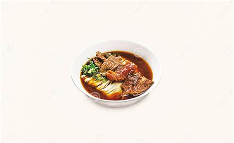 white bowl of beef noodle soup with hardboiled egg halves and sliced green onion on grey countertop