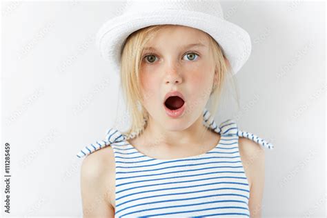 Close up portrait of amazed adorable little girl in white hat and ...