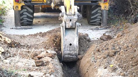 Excavator digs a trench to lay pipes. Close up of an excavator digging a deep trench. An ...