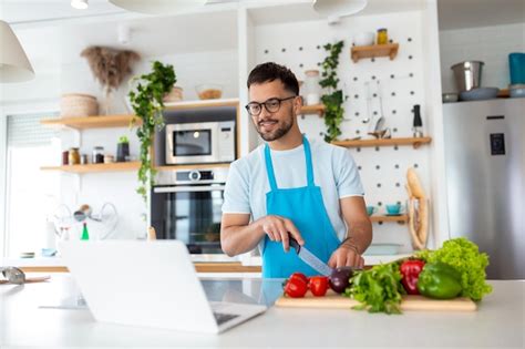 Premium Photo | Happy young man cooking healthy dinner at home he is ...