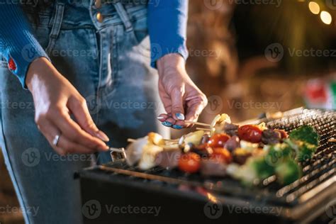 Close up hand of Woman cooking meat on barbecue grill at new year party ...