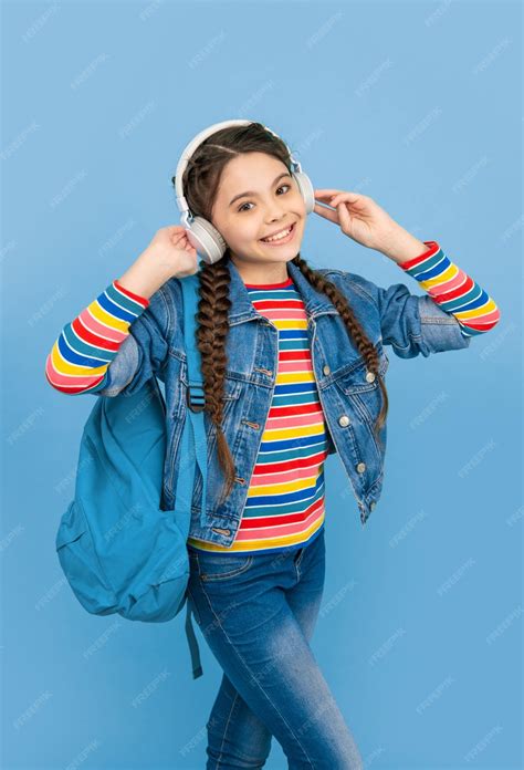 Happy teen girl listening to music in headphones blue background ...