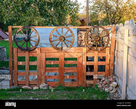 A decorative wooden fence adorned with antique wagon wheels, positioned in a vibrant outdoor ...