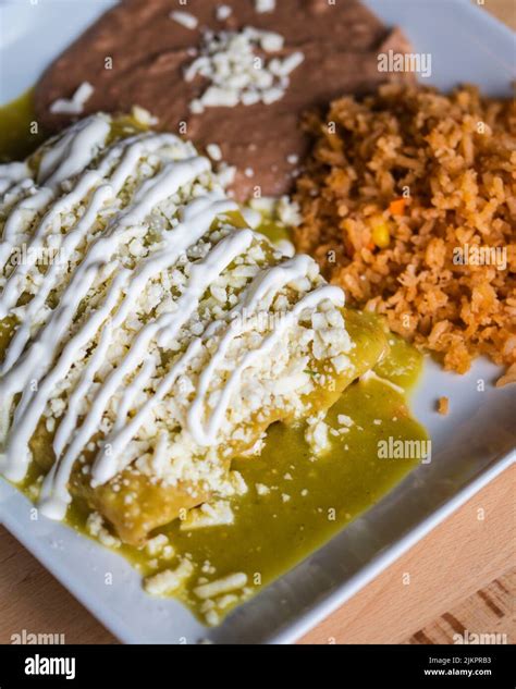 A vertical shot of a Mexican dish of enchiladas verdes with rice and ...