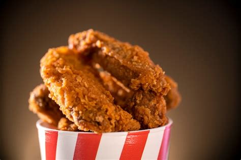 Bucket full of crispy kentucky fried chicken with smoke on brown ...