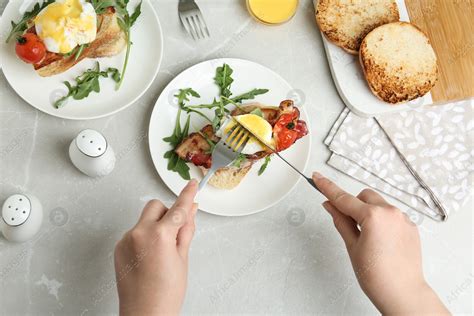 Woman eating tasty egg Benedict at light grey marble table, top view: Stock Photo | Download on ... - can pregnant women eat eggs benedict