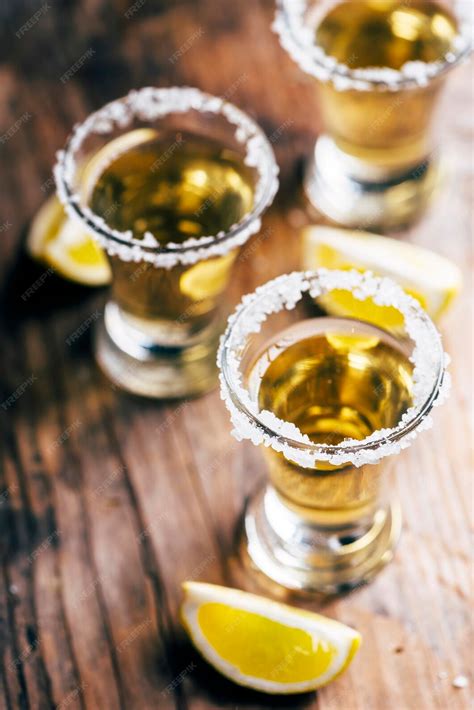 Tequila mexicano dorado en vaso de chupito con limón y sal en una mesa ...