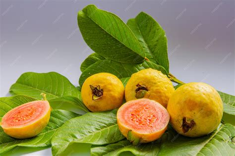 Premium Photo | Ripe yellow fruits and leaves of guava on a white ...