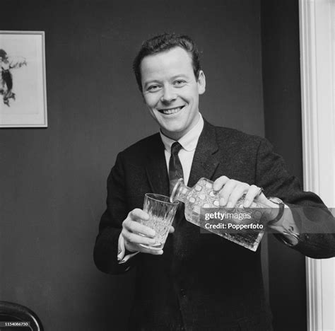 English singer Craig Douglas pours a drink from a cut glass decanter ...