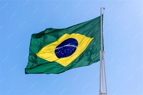 Premium Photo | Flag of brazil fluttering in the blue sky. order and progress in portuguese.
