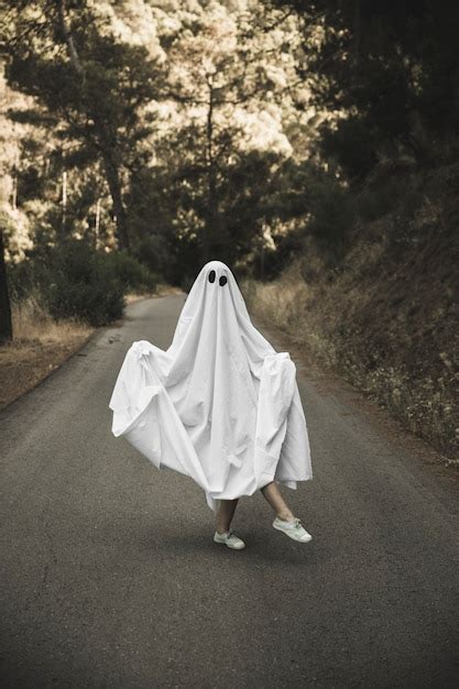 Human in ghost suit posing on countryside route | Free Photo