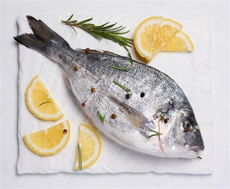 Raw whole dorado fish on white board and spices for cooking top view on ...