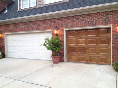 two garage doors are open in front of a brick house with potted plants ...