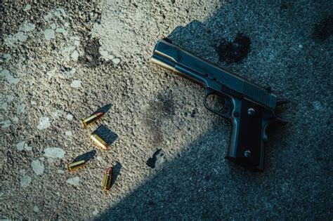 A pistol and shell casings lie on the asphalt evidence of a crime ...