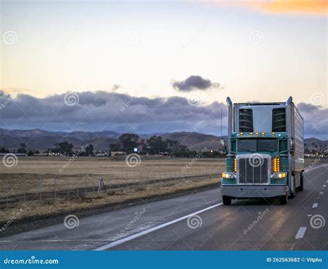 Classic Green Big Rig Semi Truck with Turned on Light Transporting Frozen Cargo in Refrigerator ...