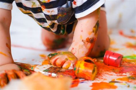 Baby crawls on the floor playing with paints | Premium Photo