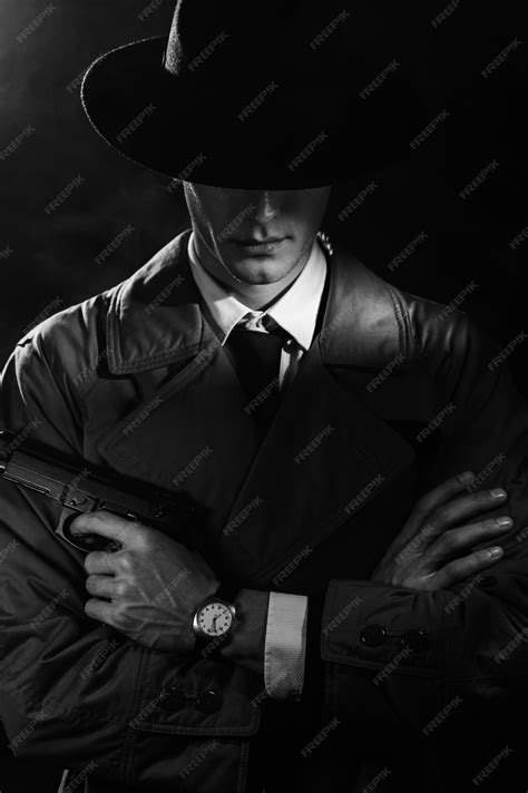 Premium Photo | A dark silhouette of a male detective in a coat and hat with a gun in his hands ...