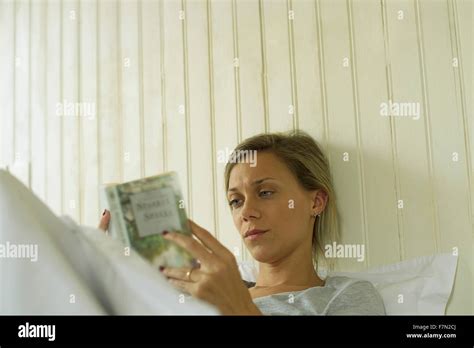 Woman reading in The Ritz-Carlton bed at a hotel