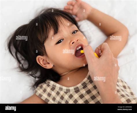 mother or doctor spraying medicine in mouth of toddler girl. baby sore ...