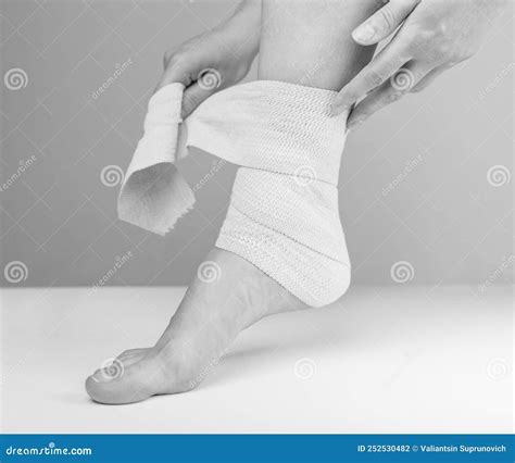 Woman Wrapping Compression Bandage Around Sprained Ankle To Reduce Ache ...