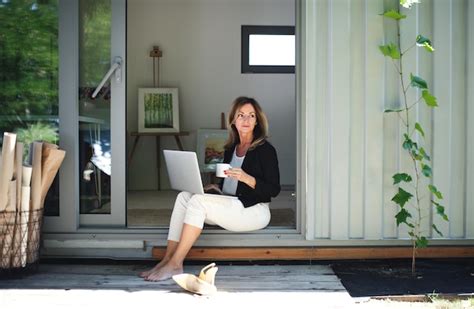 Mature woman working in home office in container house in backyard ...