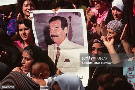 Black-and-white photo of Saddam Hussein, in a suit, with a group of women students