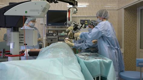 surgeons a man and two women in a large operating room perform microscopic surgery on ENT organs ...