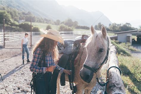 农村骑马场的年轻女青年在检查马鞍高清图片下载-正版图片501889701-摄图网