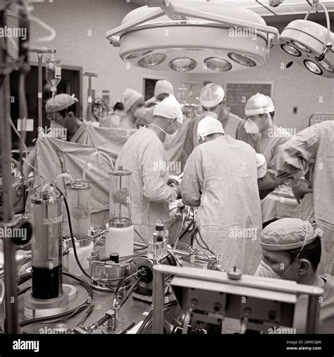 1970s SURGEON & ATTENDANT DOCTORS NURSES TECHNICIANS PERFORMING OPEN HEART SURGERY WITH THE USE ...