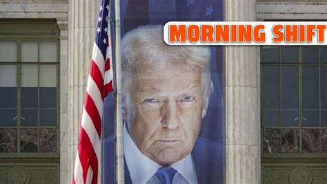 A banner showing an image of President Donald Trump is seen behind an American flag outside a US Dep Minimalist