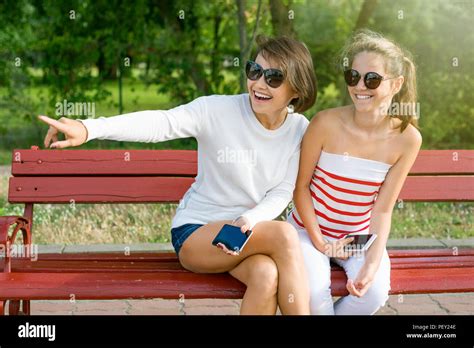 Adult daughter talking to her senior parents on a bench in a park
