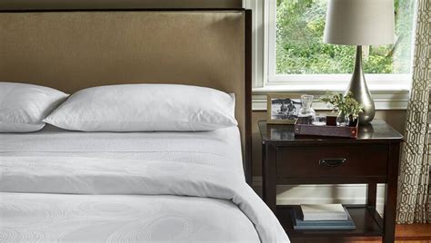 JW Marriott bed in hotel room with logo on an accent pillow