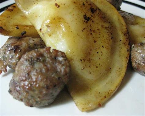 A plate with pierogies sausages and cabbage served with a small bowl of sour cream