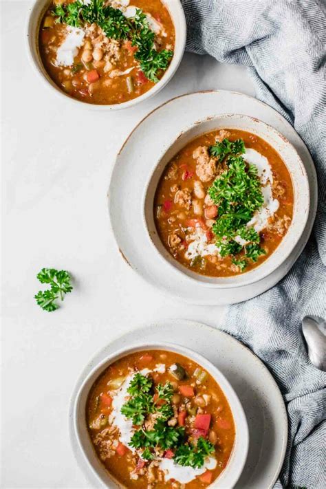 A bowl of Laura's quick slow cooker turkey chili, topped with shredded cheese, sliced green onions,