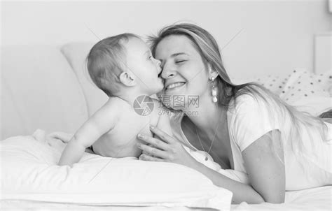 欢乐的母亲拥抱和吻在床上的婴儿男孩黑白像高清图片下载-正版图片304212758-摄图网