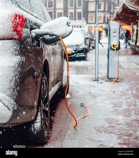 Electric car plug charging in the winter Stock Photo - Alamy