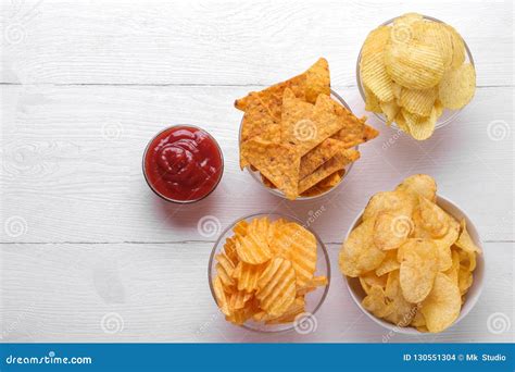 Different Types of Chips in Bowls and Red Sauce on a White Wooden Table ...