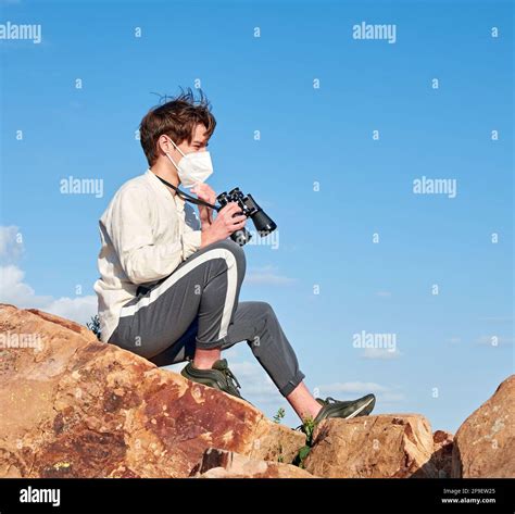 A Spanish adventurous male traveler wearing a mask sitting on a rock ...