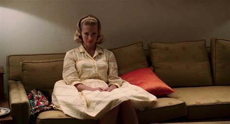 a woman sitting on top of a couch in a living room next to a lamp