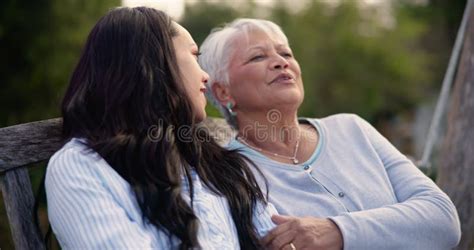 Adult daughter talking to her senior parents on a bench in a park